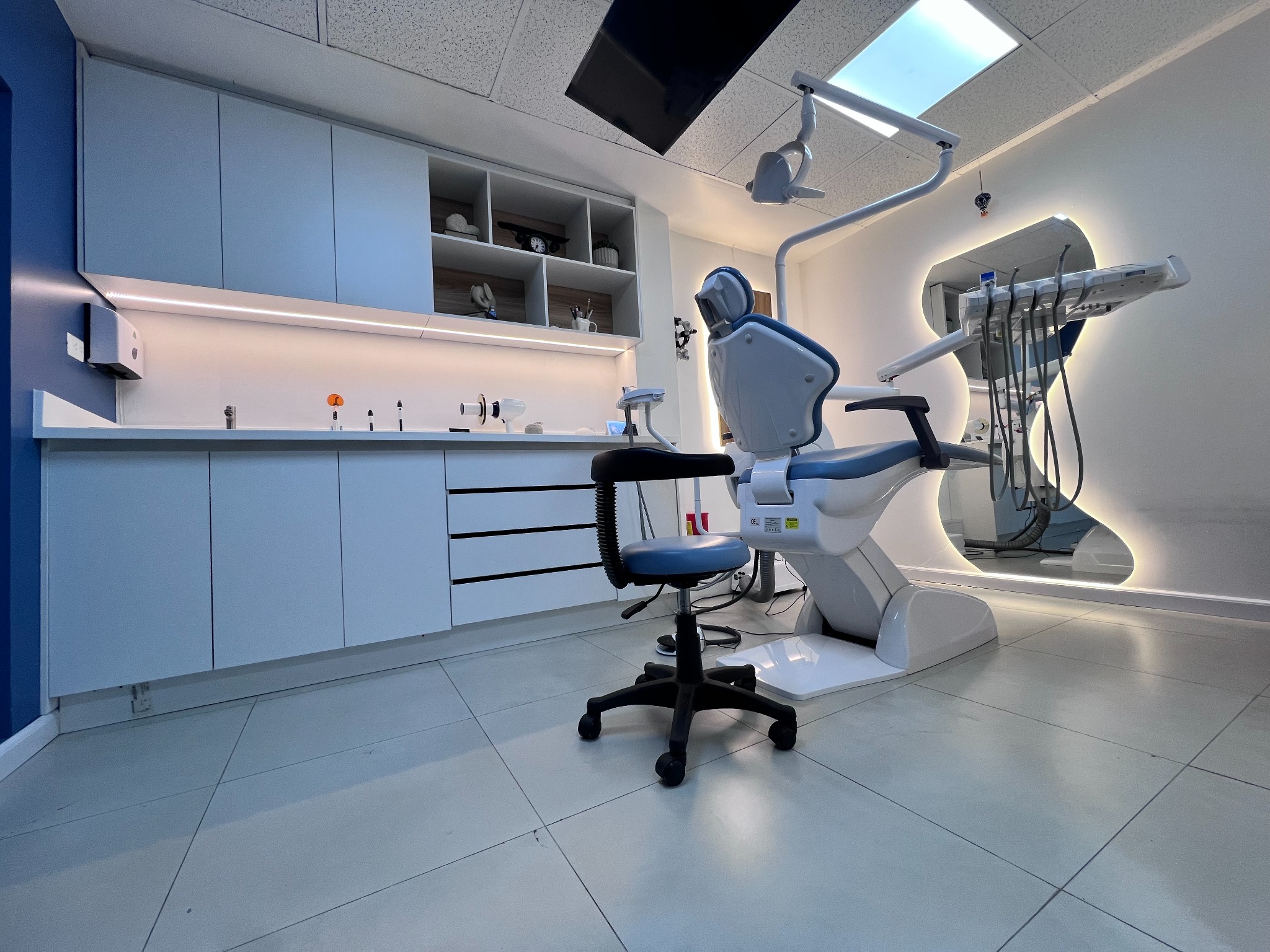 Consultorio de SANTÉ con sillón dental, mobiliario azul y pantalla en el techo